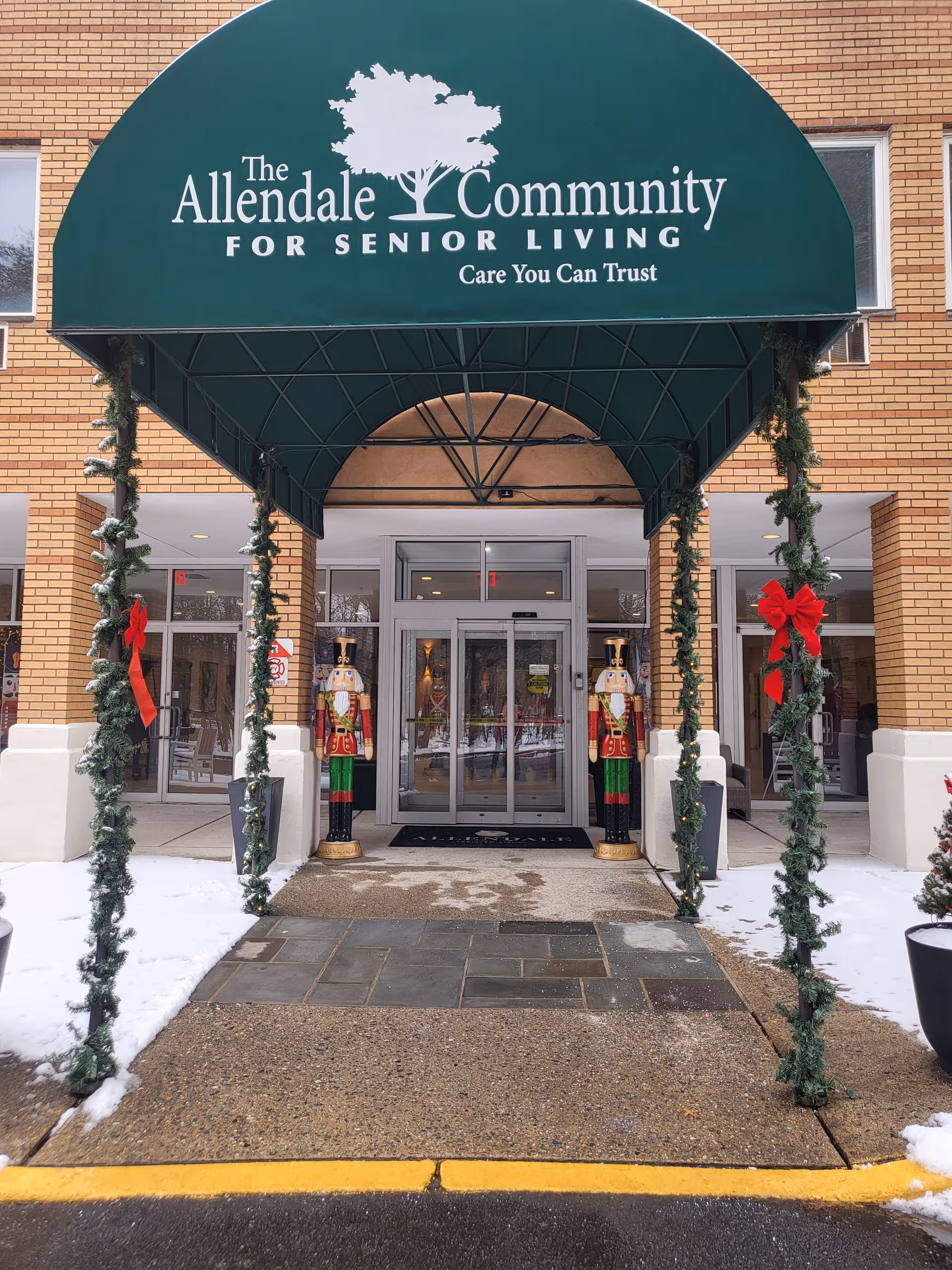 Entrance to Allendale Community for Senior Living with a green awning and holiday decorations.