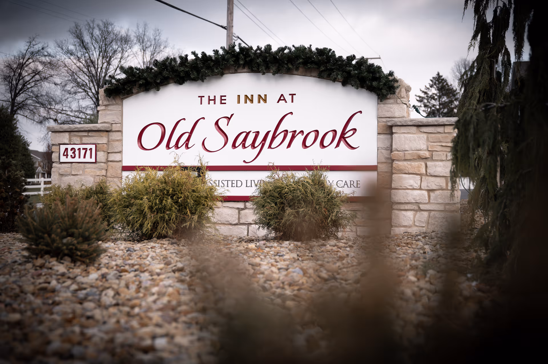 Front entrance sign reading The Inn at Old Saybrook, stone pillars, and rocky landscaping.