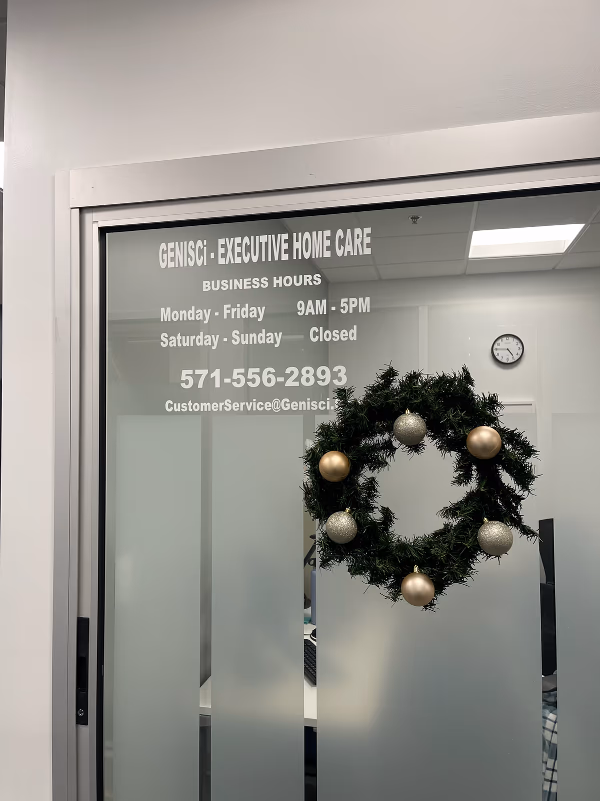 Frosted glass door with a holiday wreath inside a facility, displaying Executive Home Care signage.
