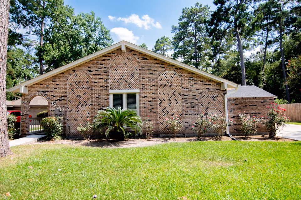 Brick, single-story building with a manicured lawn and flowering shrubs in front yard.