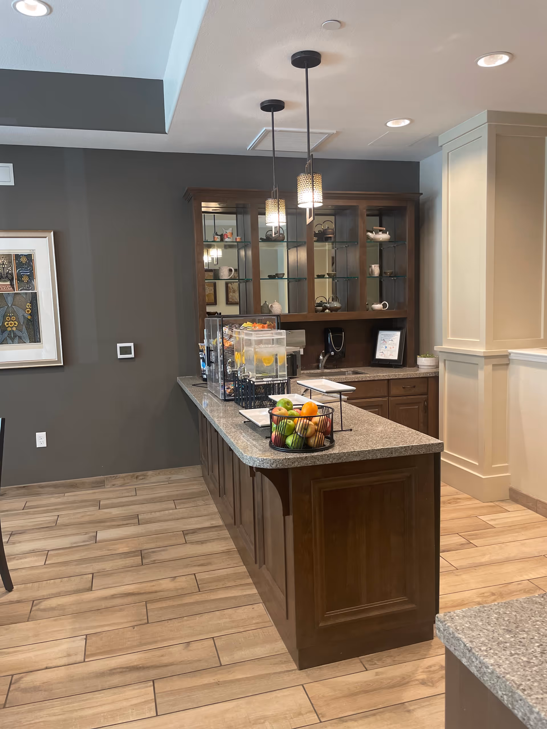 Modern service island with fruit basket and glass cabinets in a facility kitchen.
