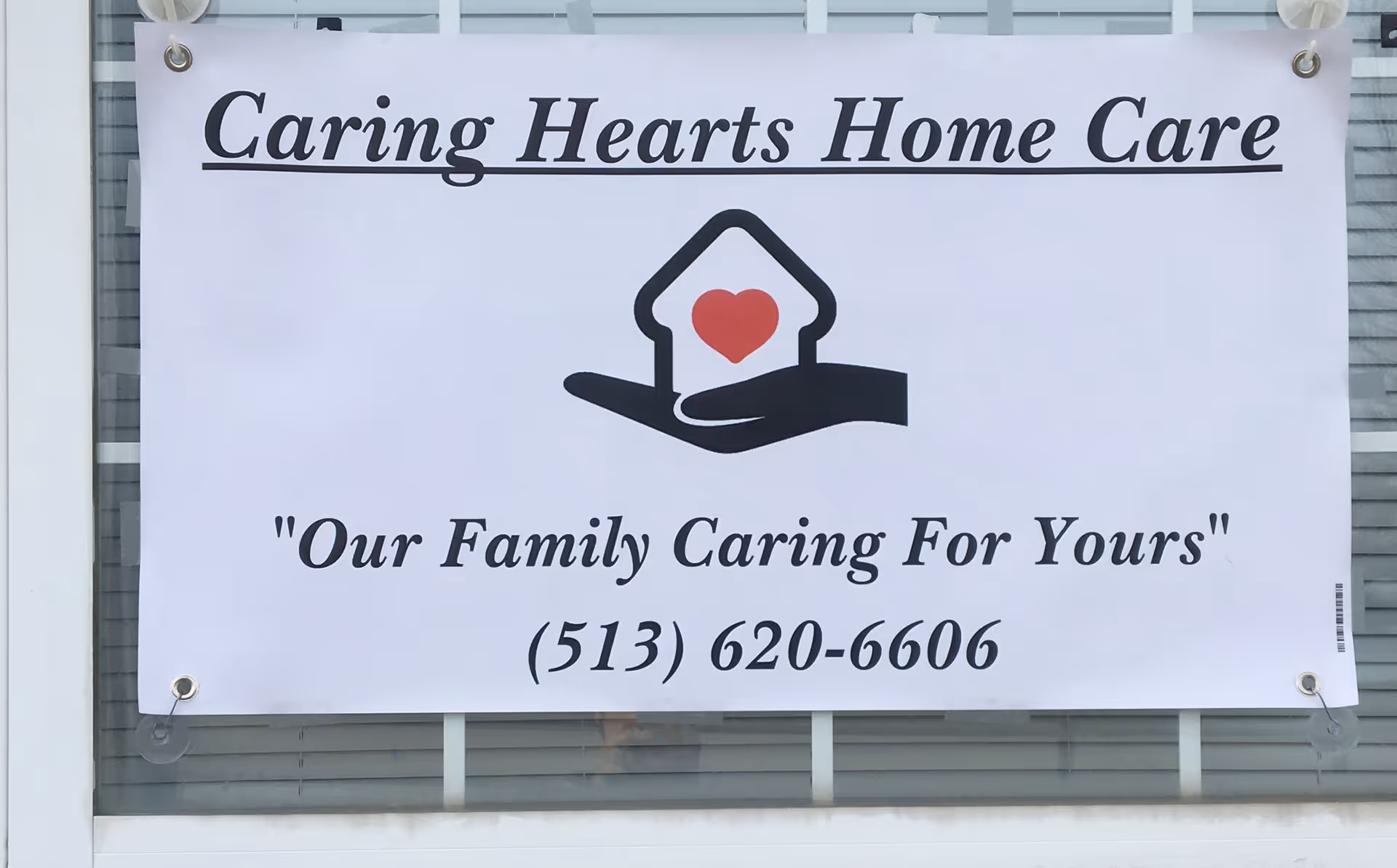 A banner on a building reads Caring Hearts Home Care with heart logo and phone number.