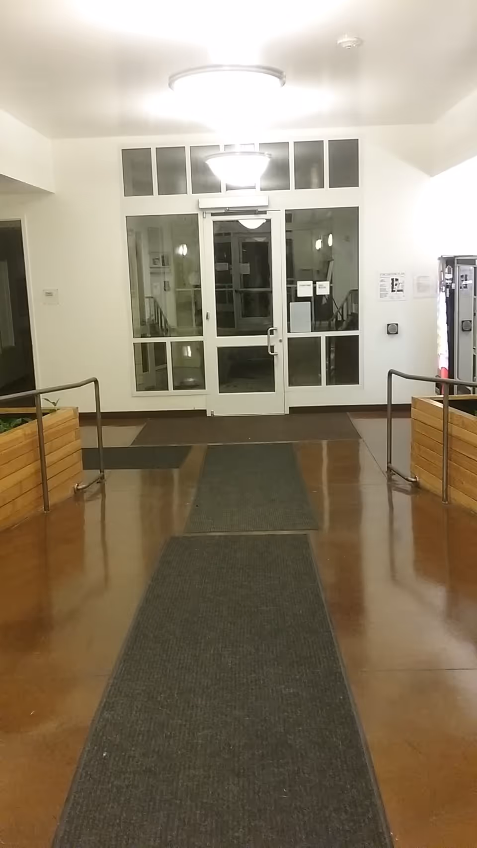 Bright interior hallway with glass doors at the end and wooden planters along sides.