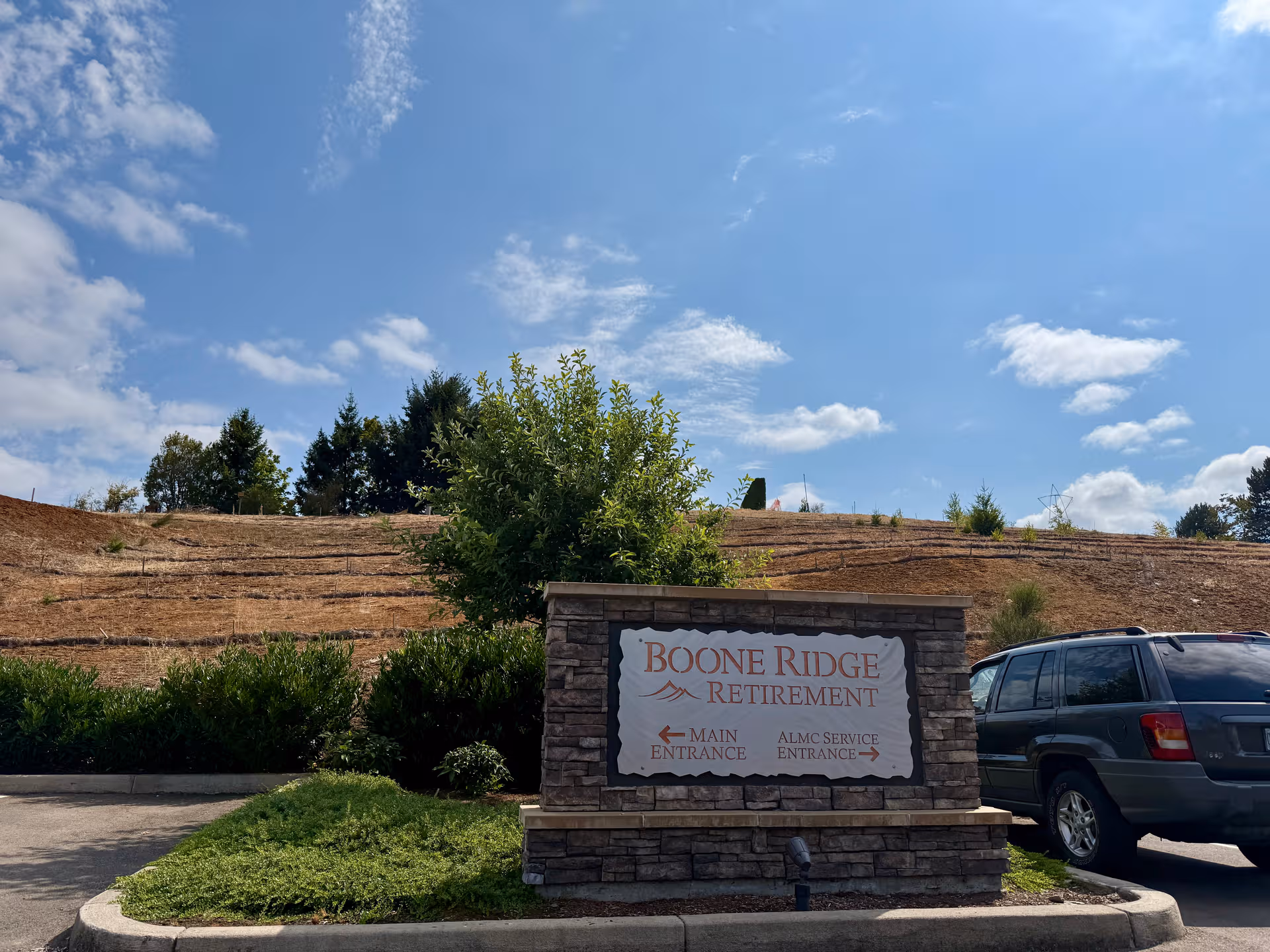 Exterior view of Boone Ridge Retirement Community sign with SUV and landscaped grounds.