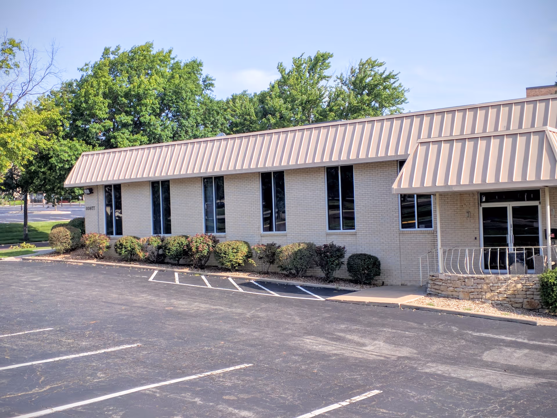 Single-story brick building with metal roof and landscaped front entrance.