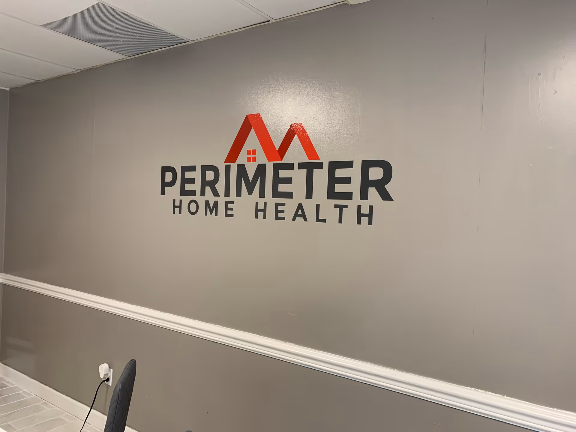 Interior hallway wall features Perimeter Home Health logo and baseboard molding.