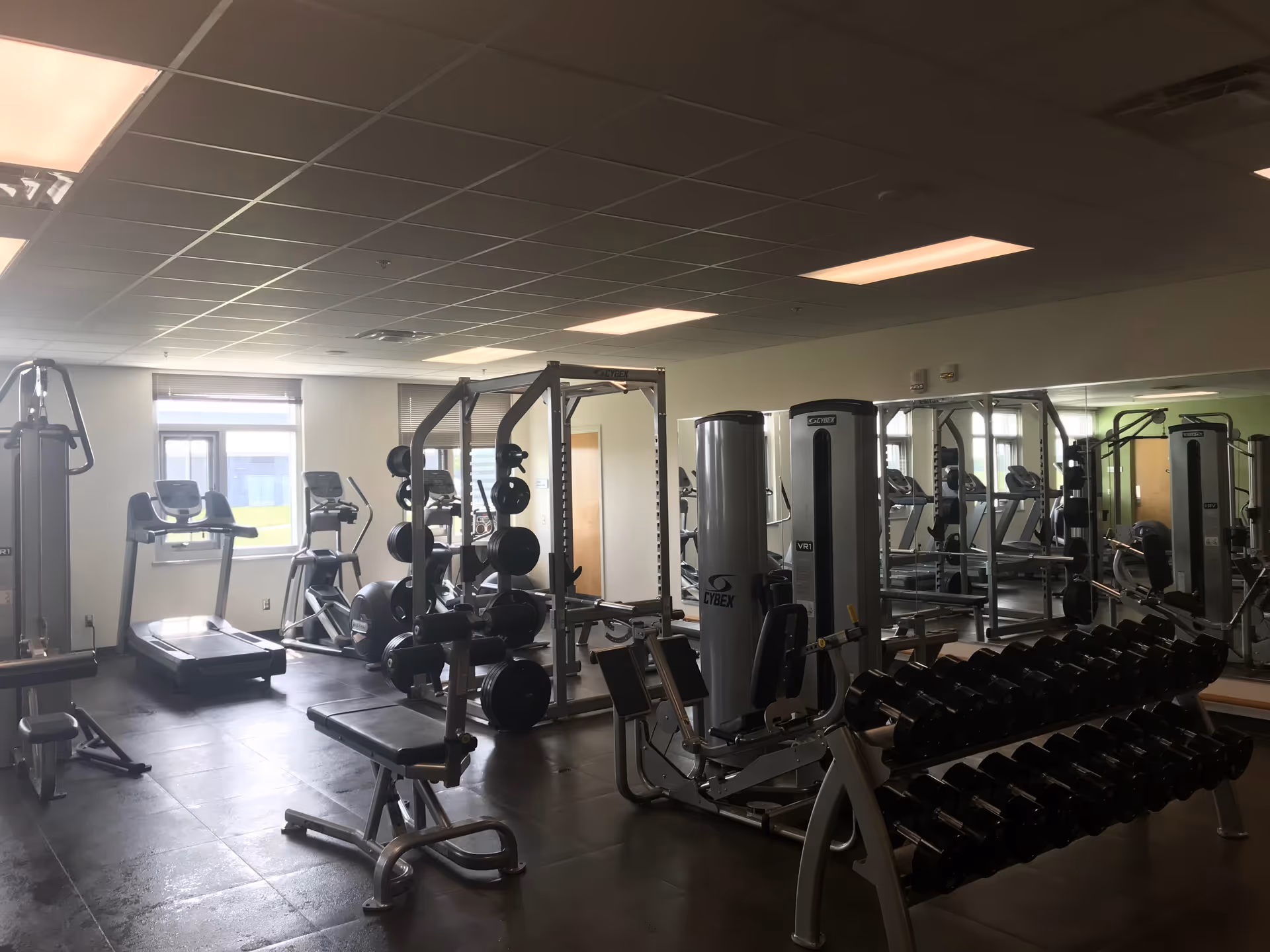 Well-equipped senior living gym with treadmills, weight machines, benches, and free weights.