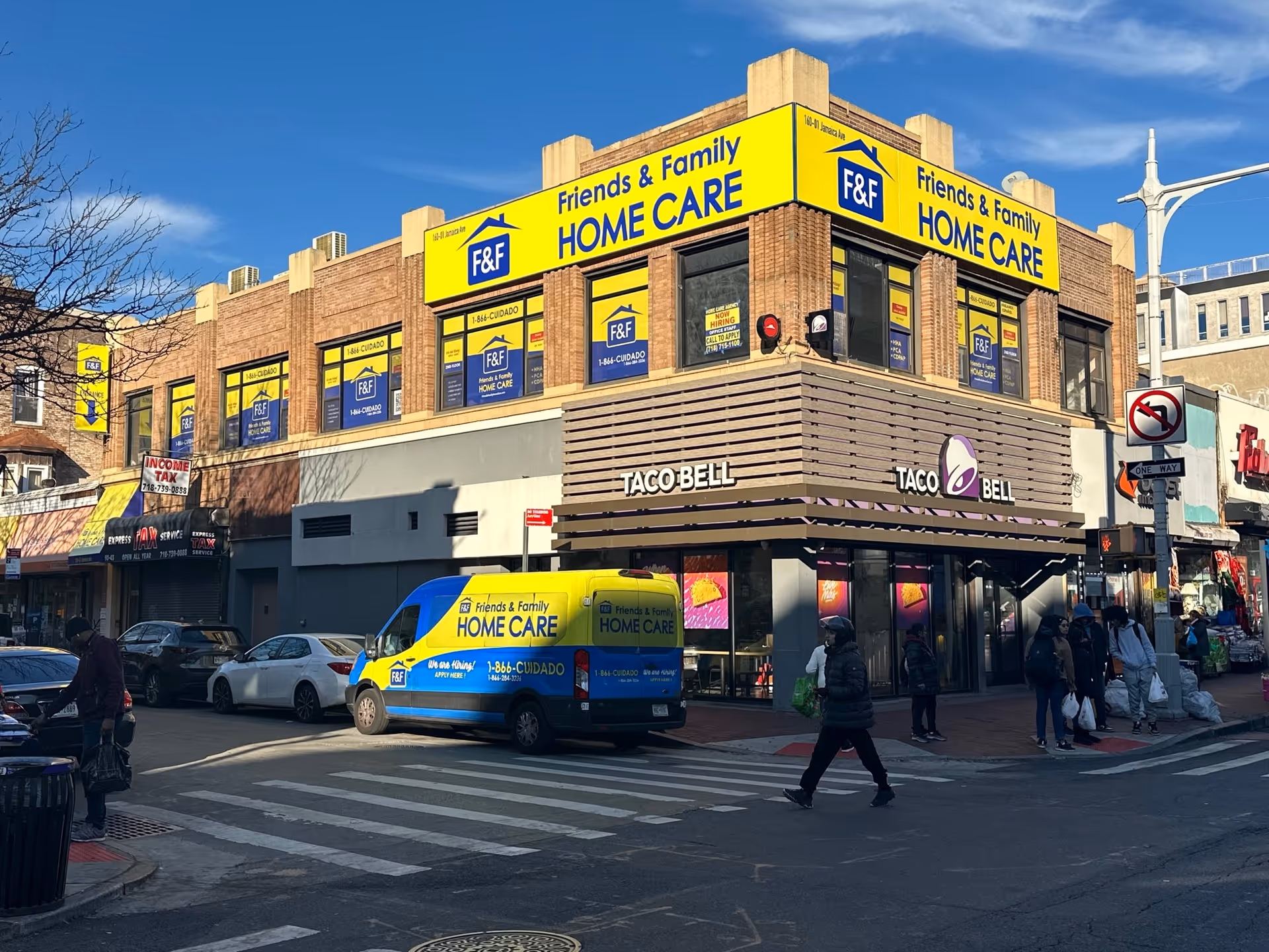 Busy city street corner with Friends & Family Home Care signage atop a Taco Bell building.
