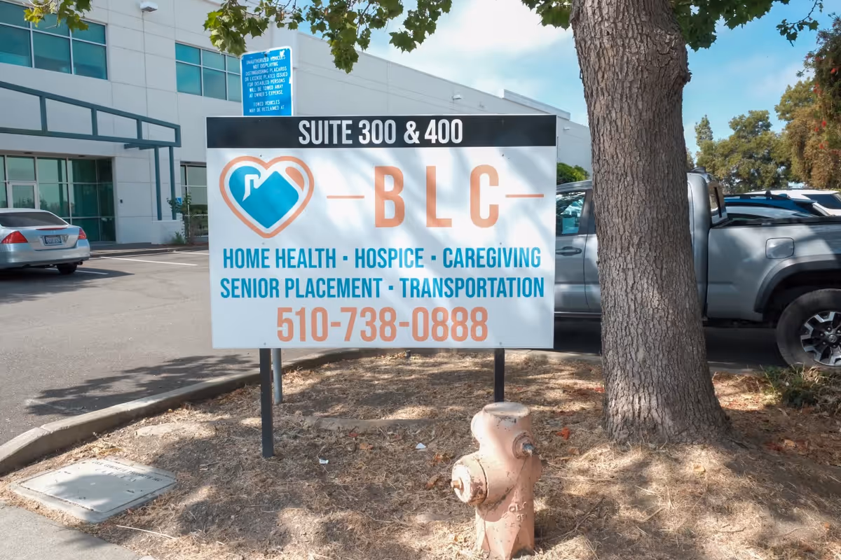 Exterior parking area with a large Best Living Care sign advertising home health and senior services.