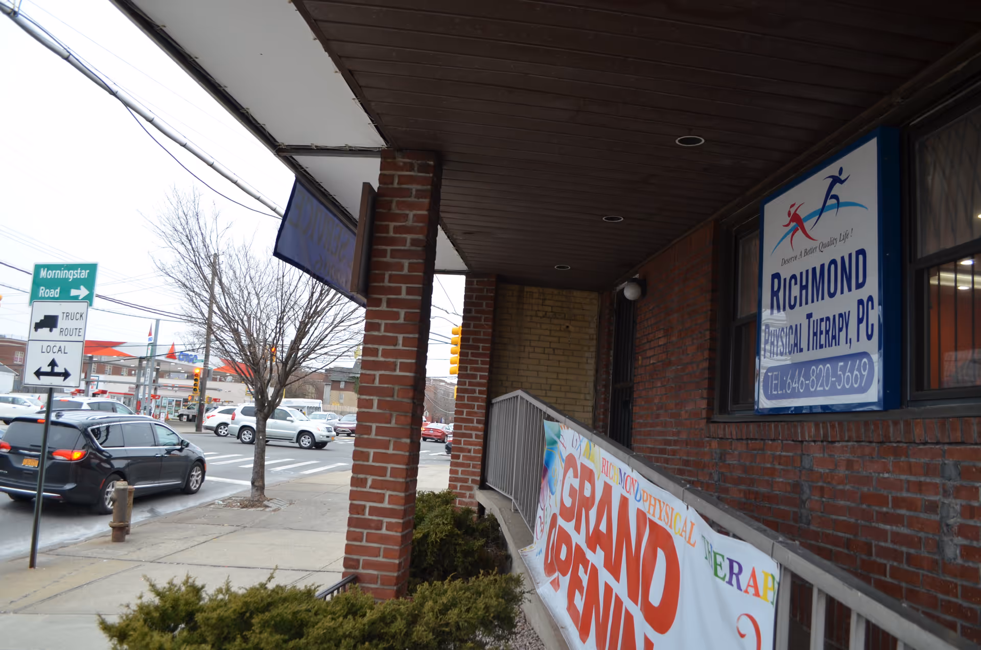 Exterior view of a brick building with Richmond Physical Therapy sign and Grand Open banner.