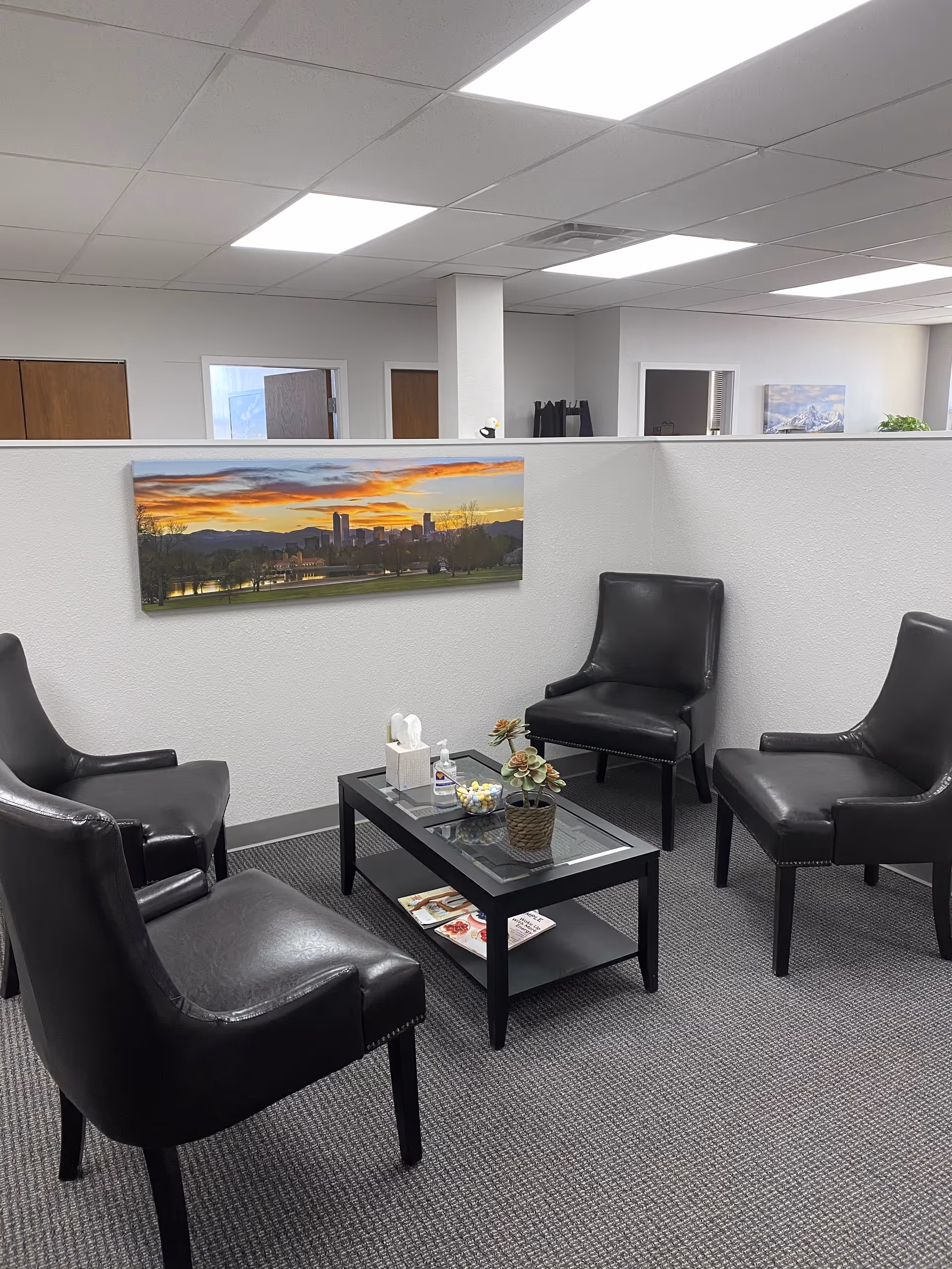 Waiting area with black leather chairs around a glass coffee table.