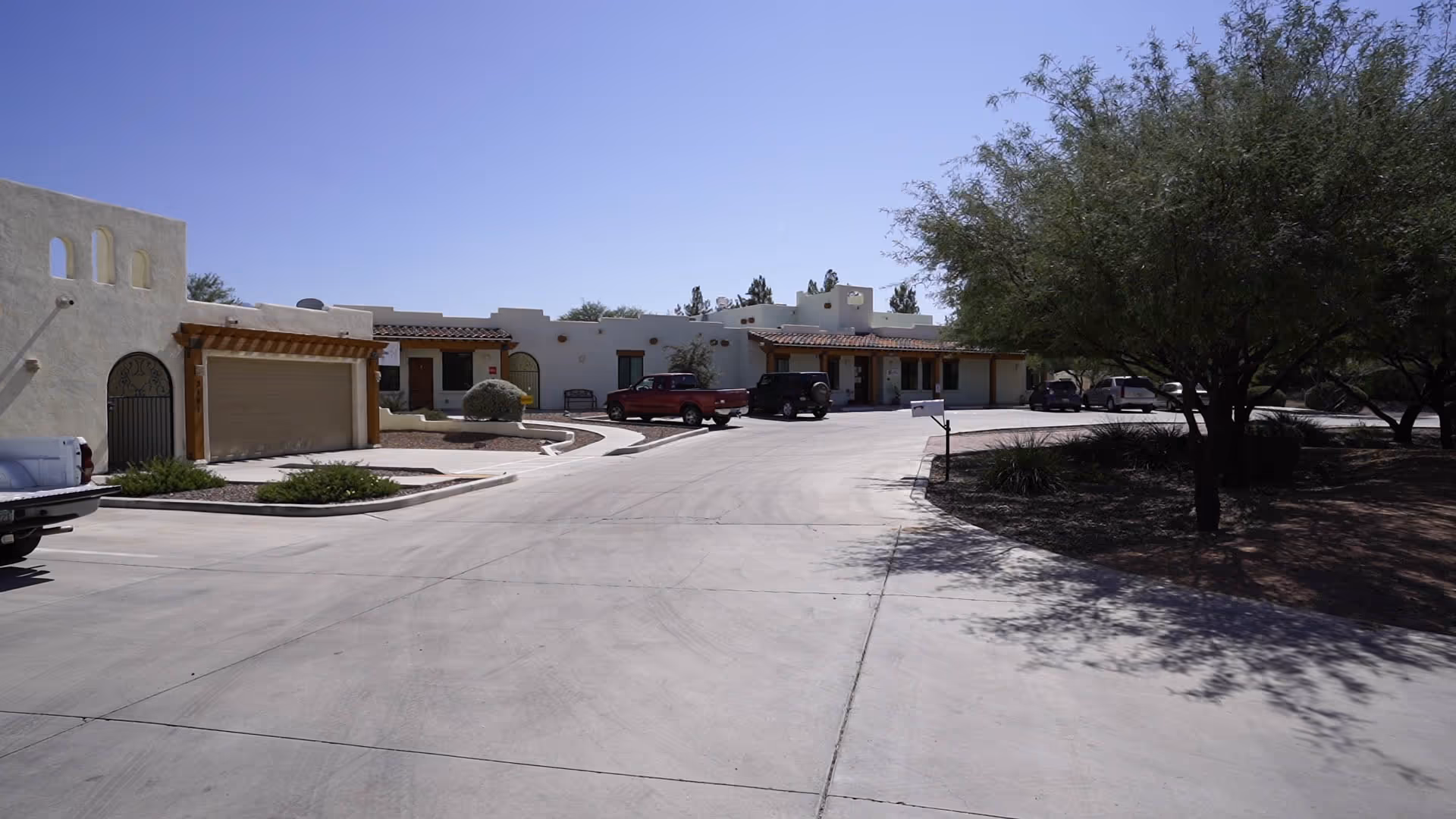 Exterior view of BeeHive Homes of Sierra Vista with driveways, parked cars, and trees.