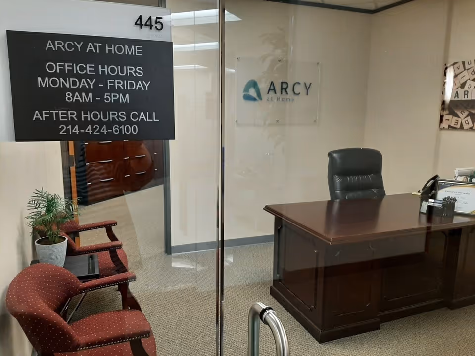 Reception desk, chairs, and a sign reading Arcy at Home in a facility lobby.