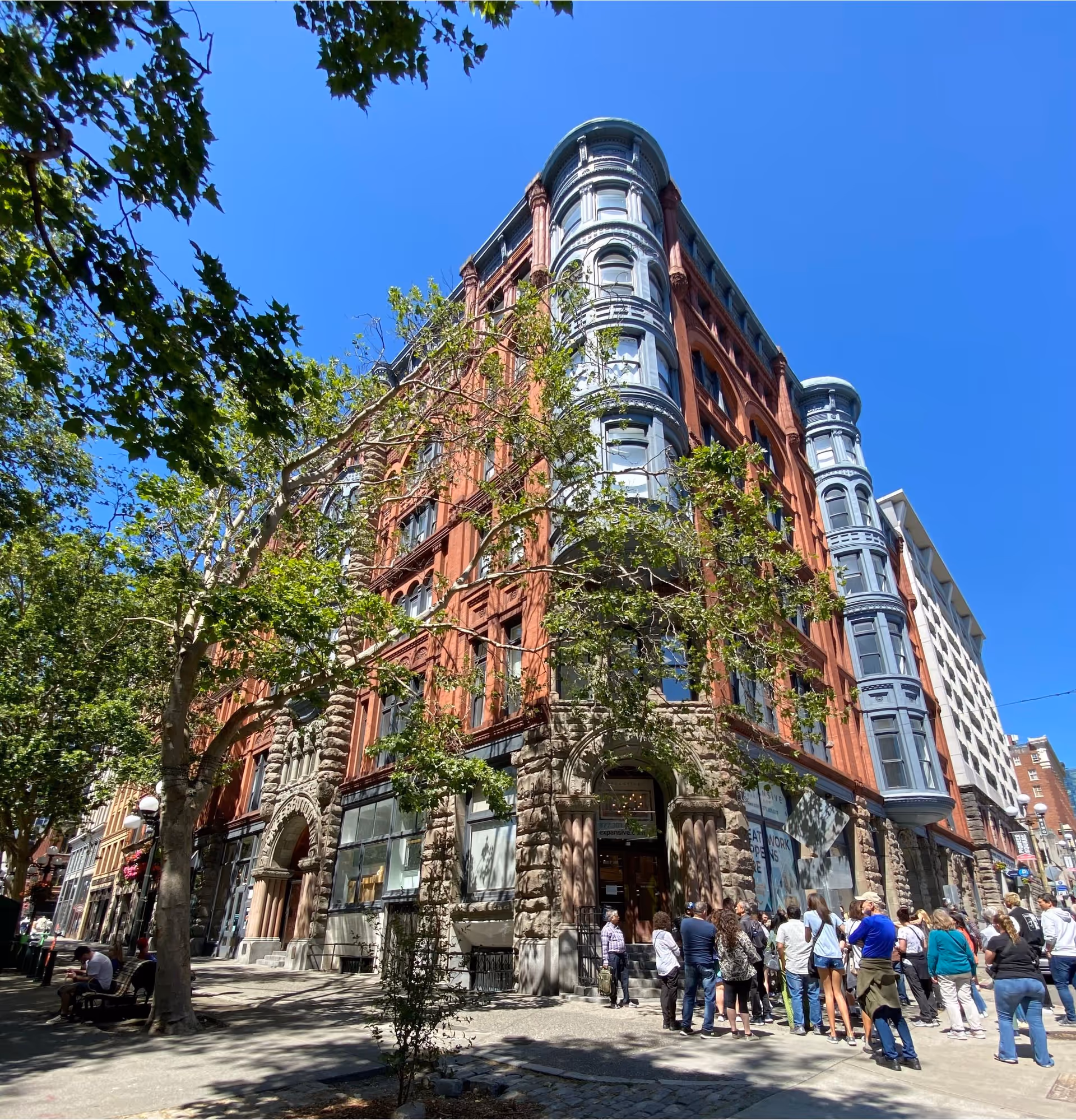 Red-brick curved-window building on a city street with people gathered outside
