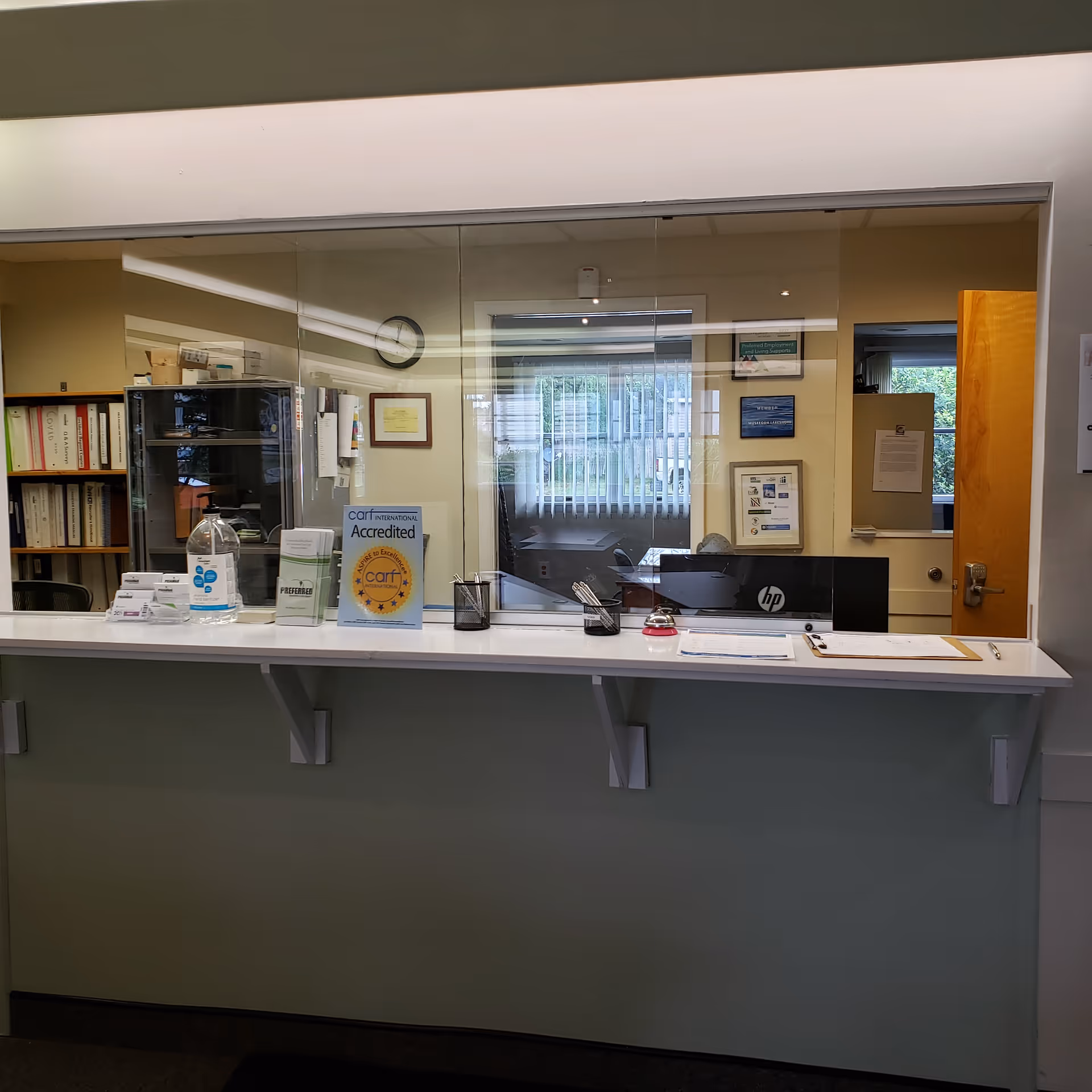 A reception counter inside a senior facility with a glass partition and documents.
