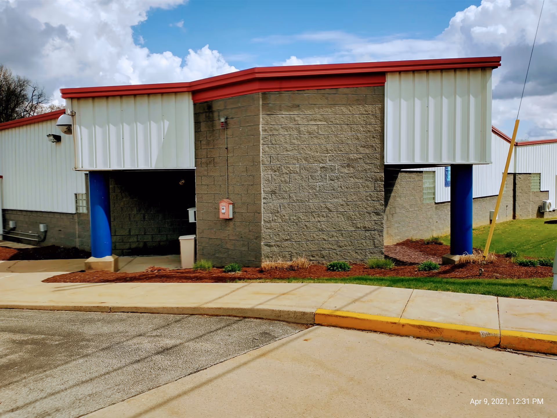 Exterior view of a care facility with brick walls, white siding, red trim, and blue columns.