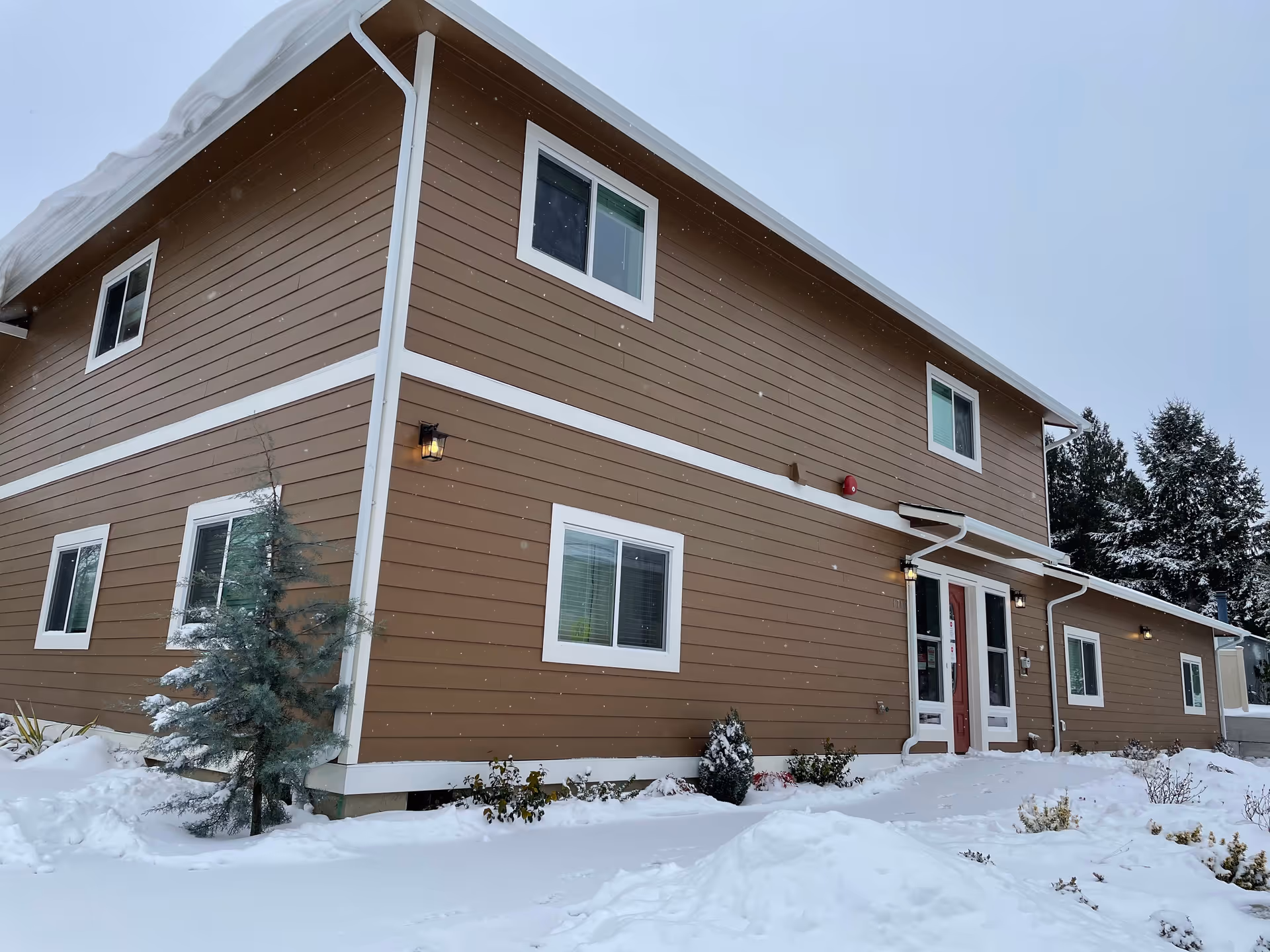 Two-story brown building with white trim, snow around, entrance doors visible.