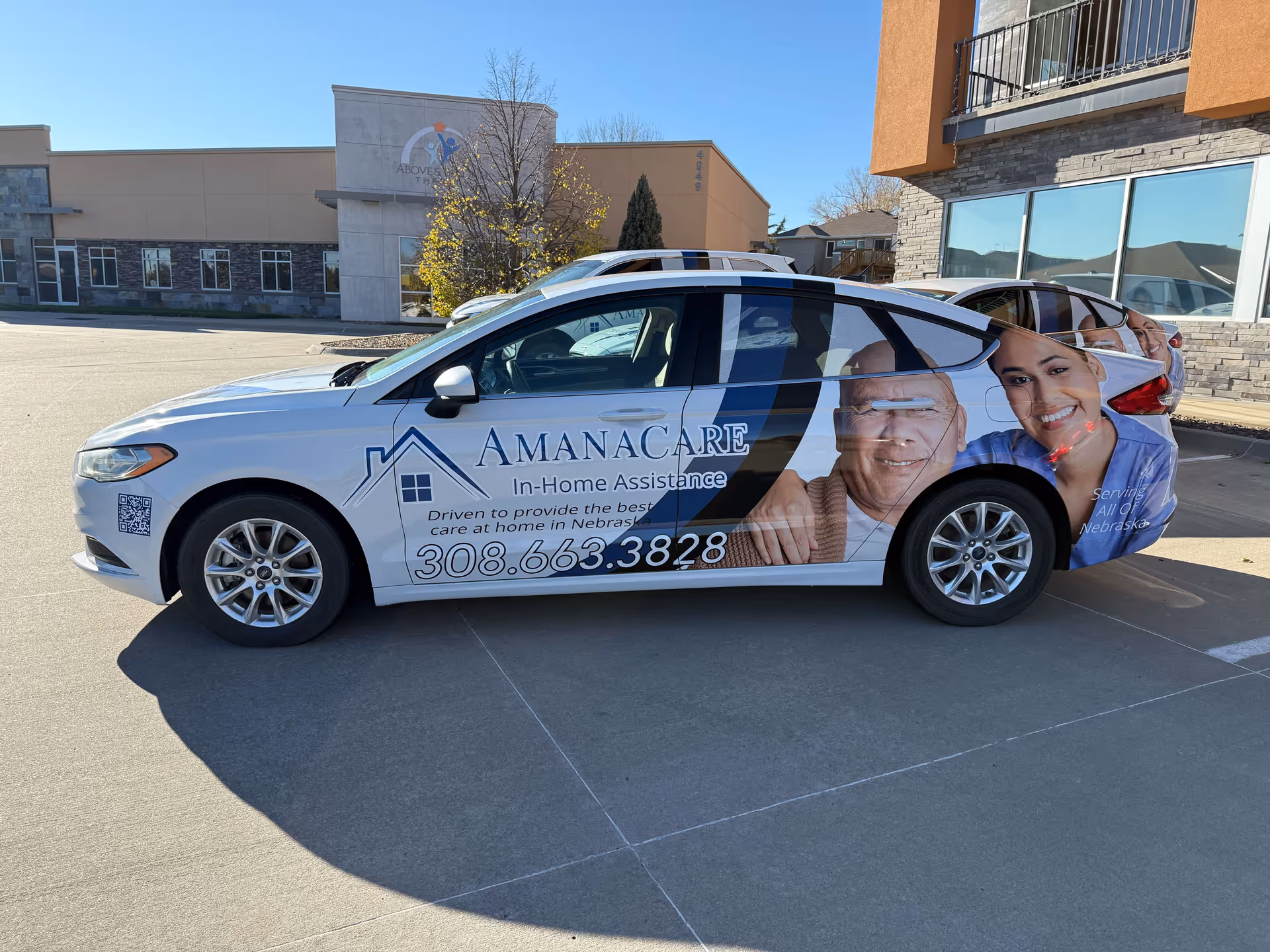 Branded AmanaCare vehicle with in-home assistance graphics parked outside a facility.