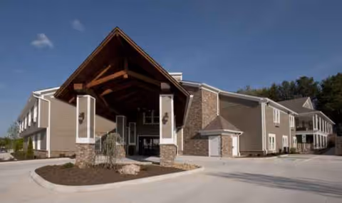 Senior living facility exterior with a covered entrance and landscaped driveway.