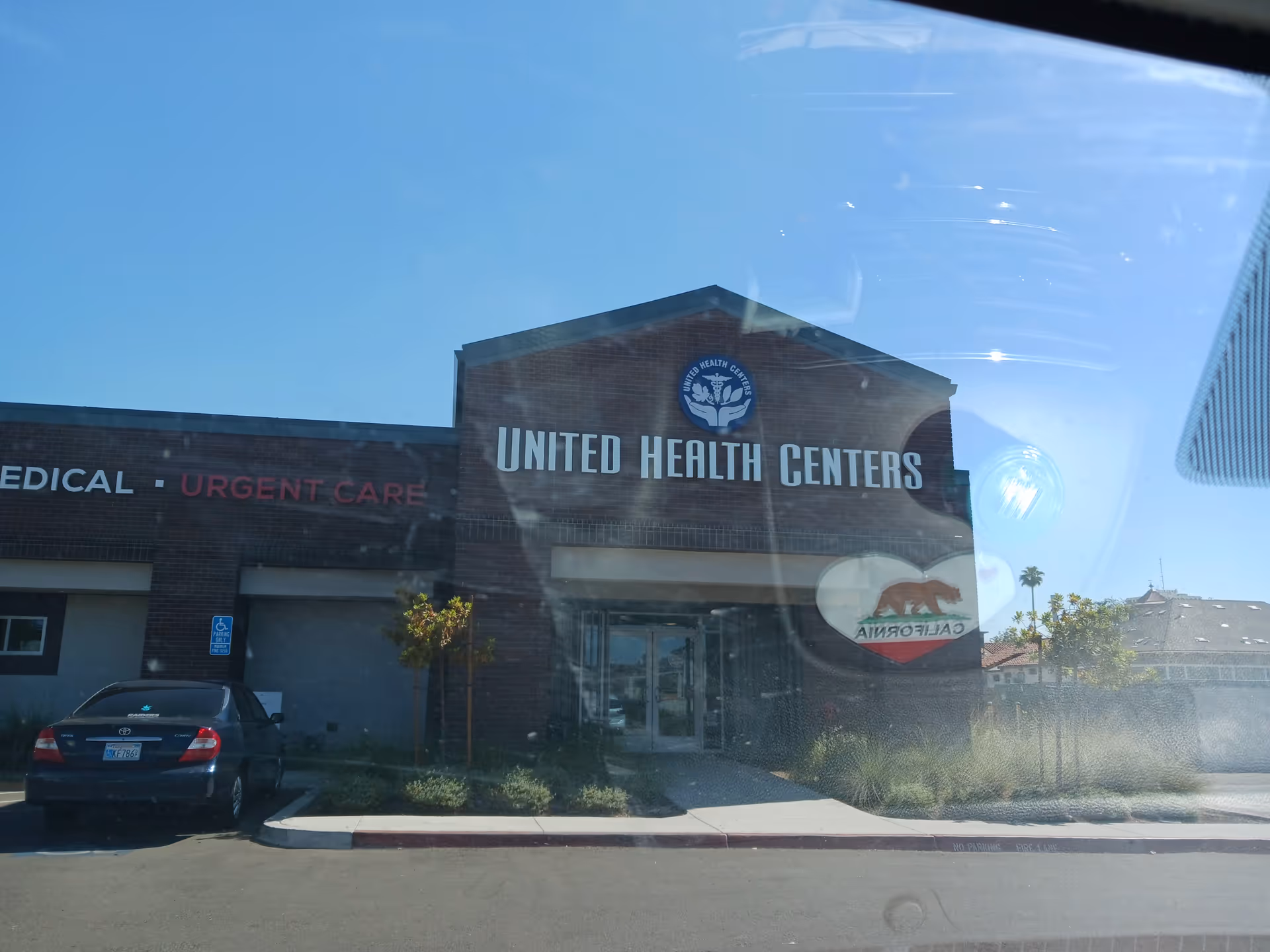 Exterior view of a building with United Health Centers sign and a parked car.
