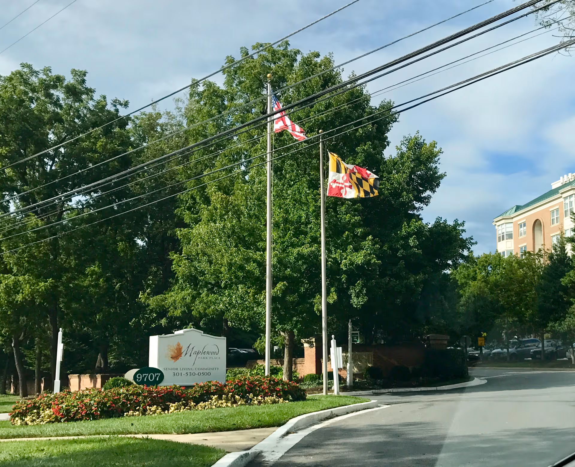 Exterior view of Maplewood Park Place entrance with flags and landscaping.