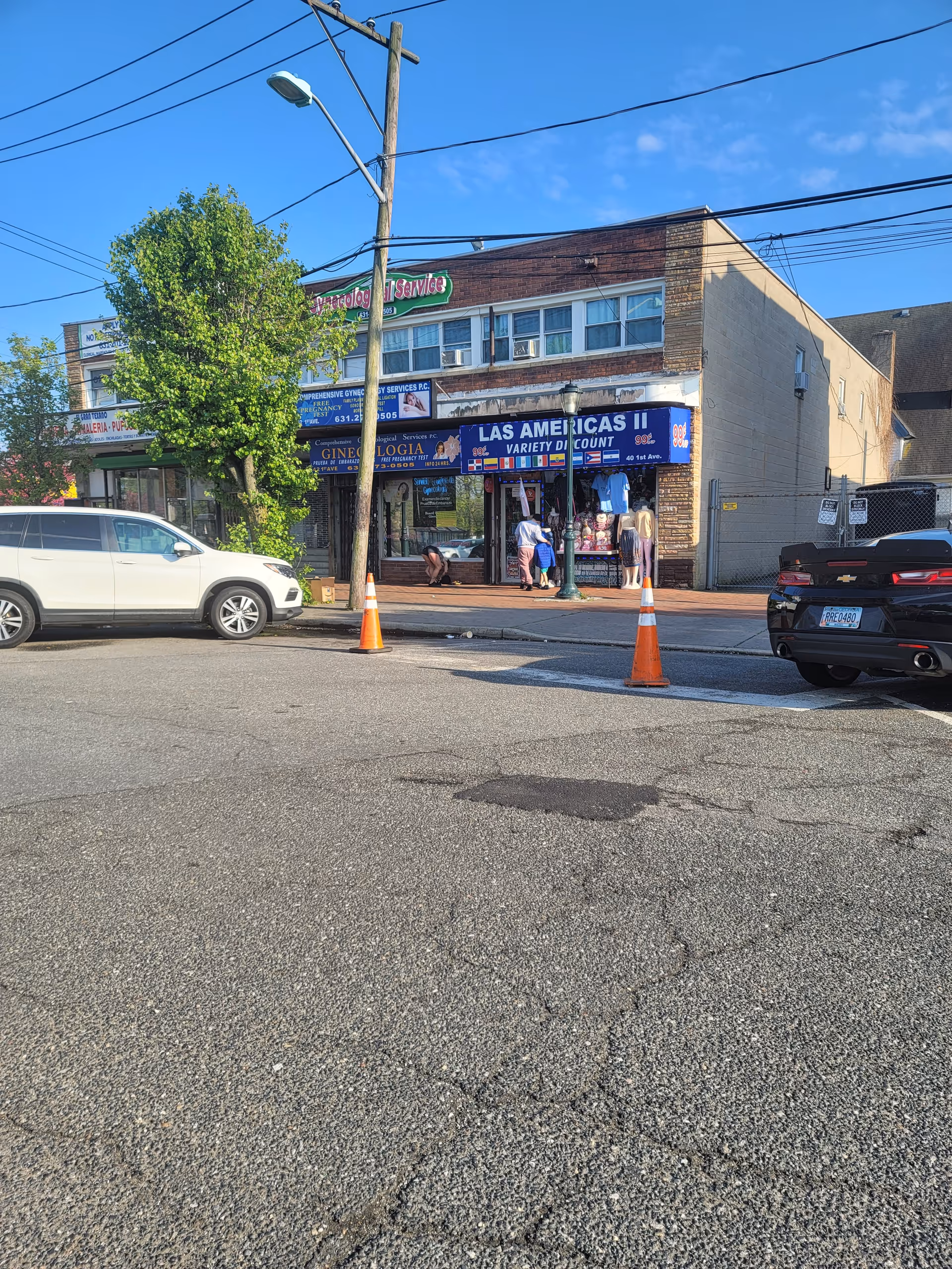 Exterior street view of storefronts with signs and parked cars.