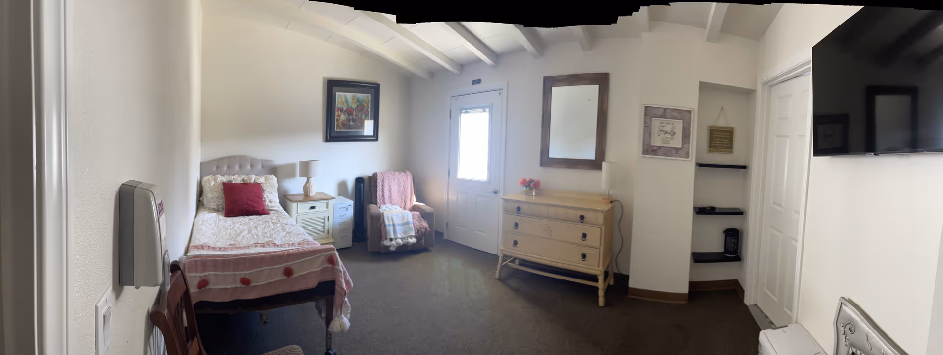 Cozy bedroom in Polly's Place with bed, dresser, chair, and TV.