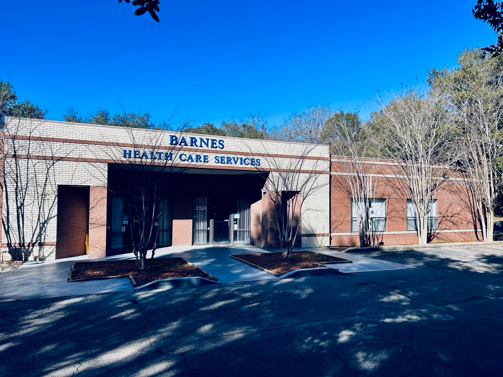 Brick facility exterior with Barnes Health Care Services signage and a shaded entrance.