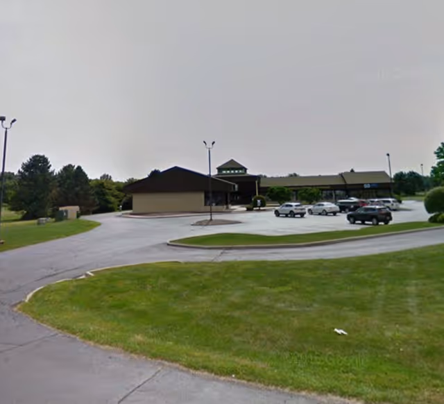 Front view of a single-story facility with a parking lot and curved driveway.