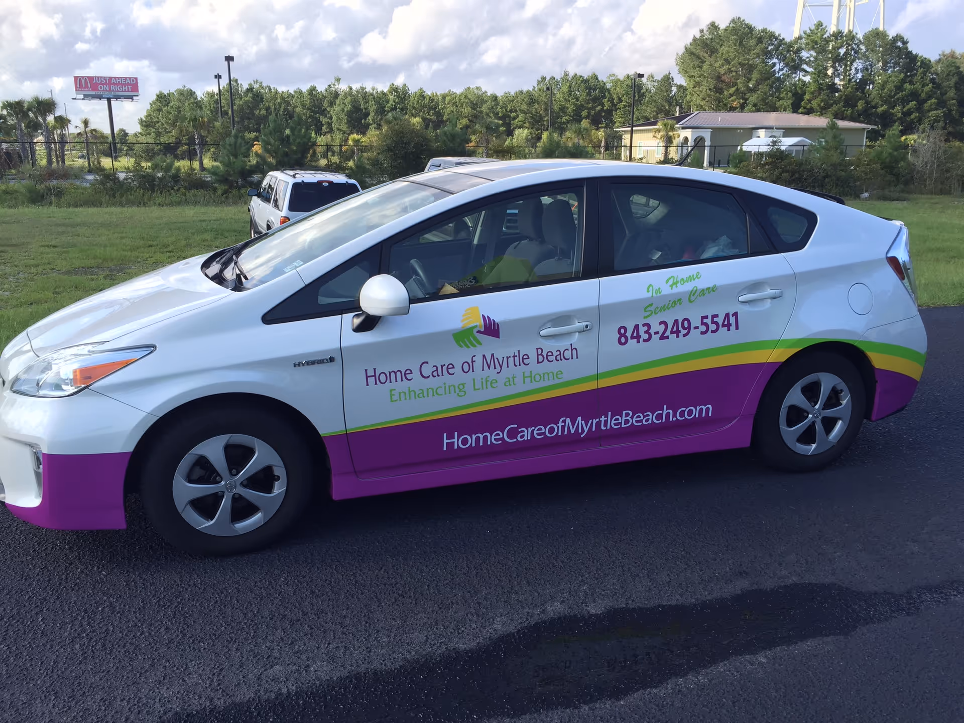 White promotional car with colorful Home Care of Myrtle Beach branding parked on a road