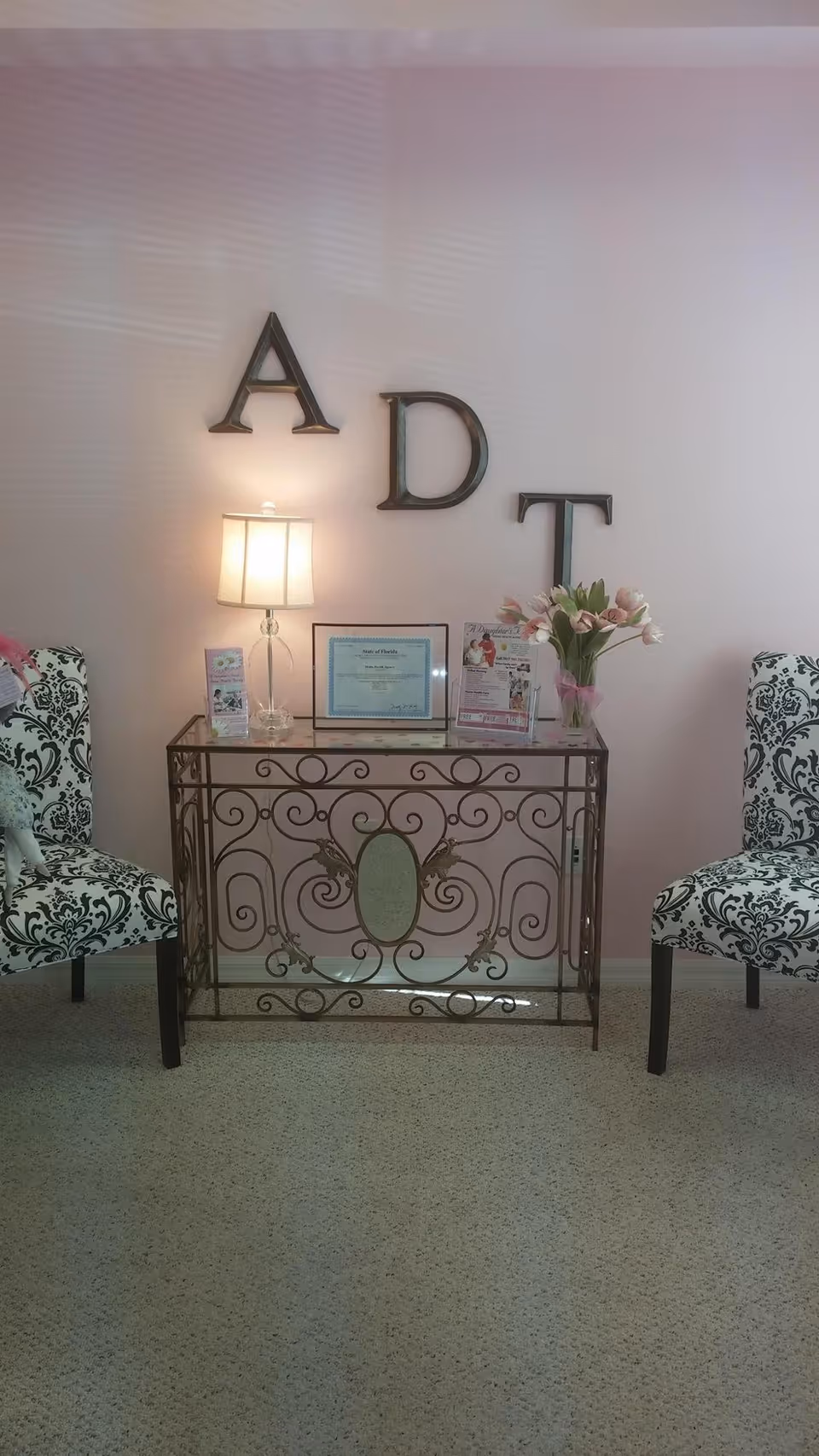Interior lobby area featuring a decorative metal console table, lamp, flowers, and patterned chairs.
