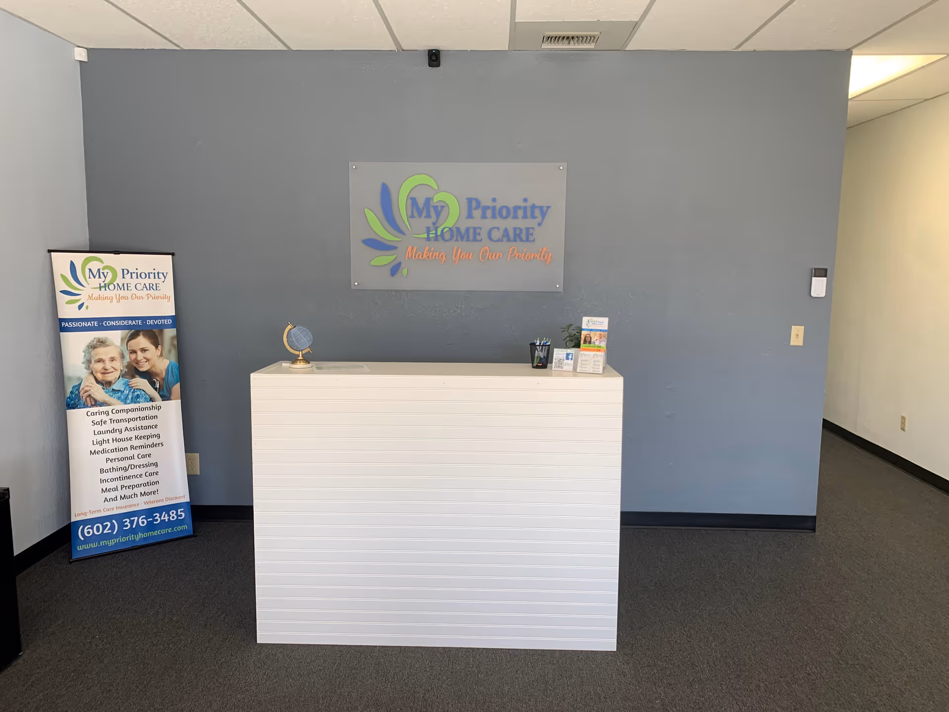 Reception area with white counter and My Priority Home Care sign on blue wall