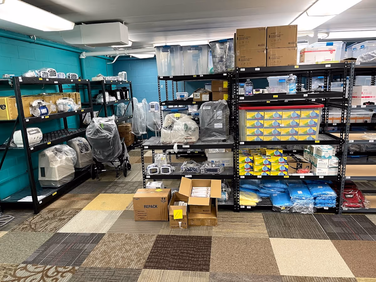 A cluttered supply room with shelves stocked with medical equipment and boxes.