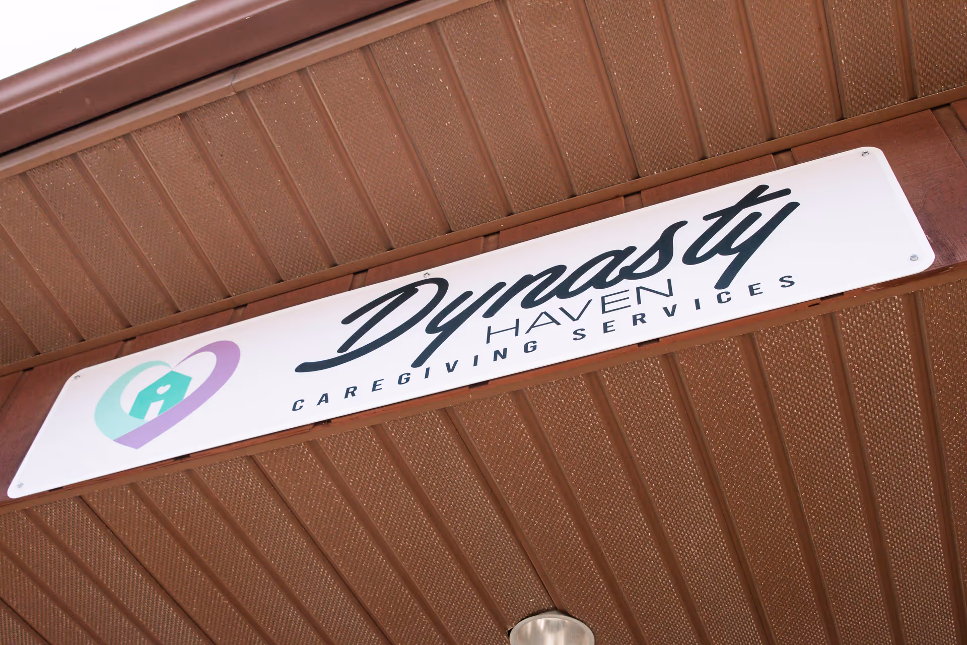Exterior view of Dynasty Haven Caregiving Services sign on a brown metal overhang.