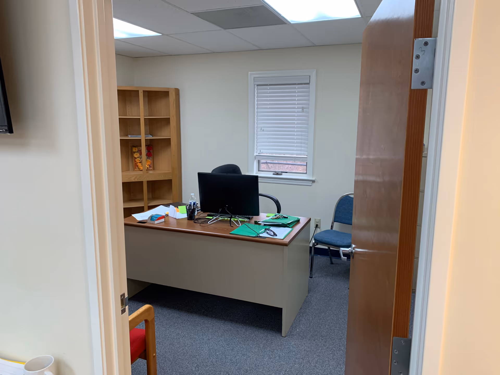Office inside a senior living facility with desk, computer, and shelves.