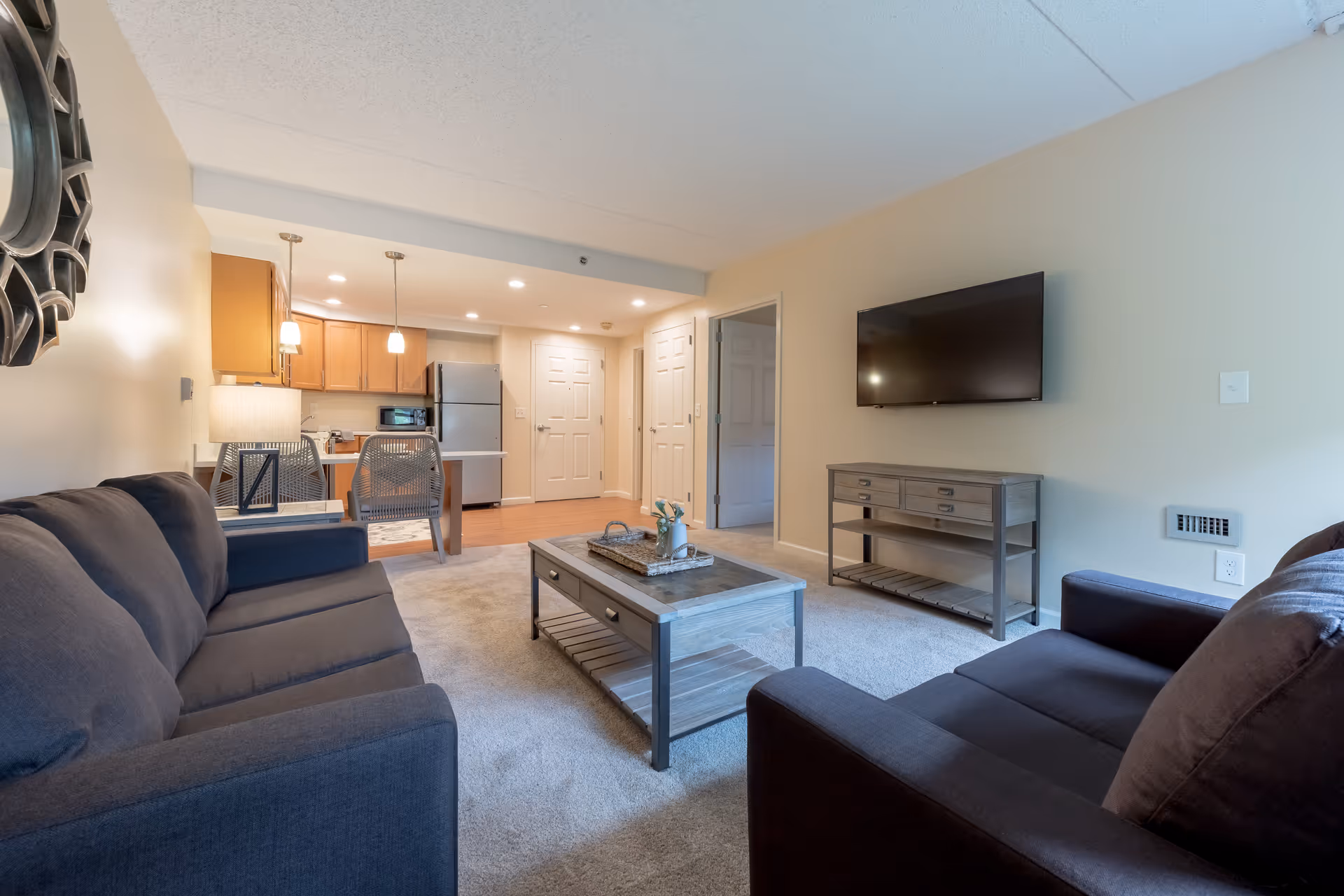 Open-concept living room in a senior living community with couches, coffee table, and TV.