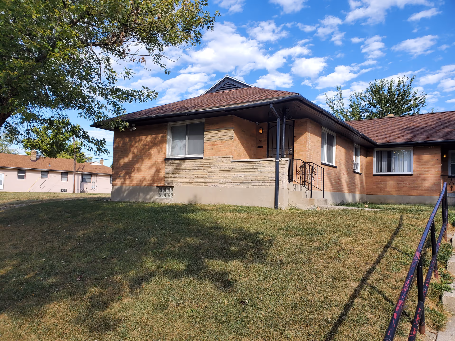 Single-story brick facility with a sloped roof, entrance steps, and a grassy yard.