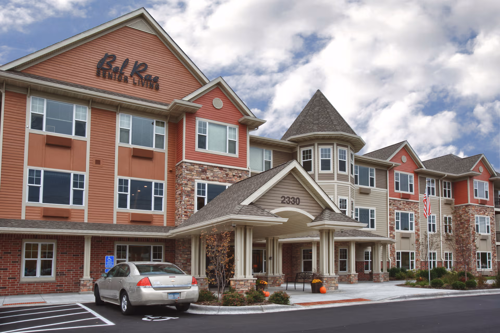 Exterior view of Bel Rae Senior Living facility with entrance, parked car, and walkway.
