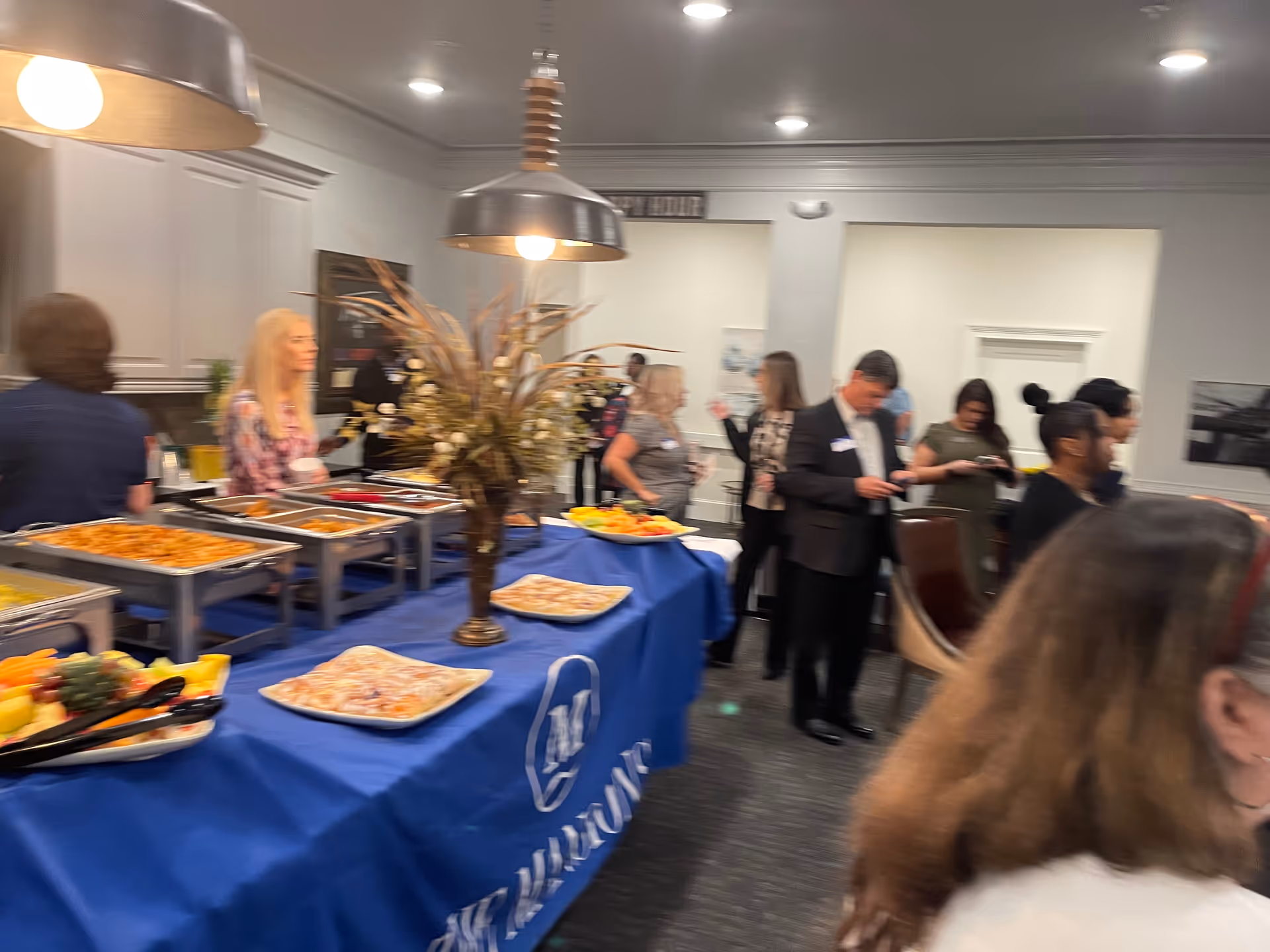 Interior dining area with a buffet line and guests mingling at a senior care event.
