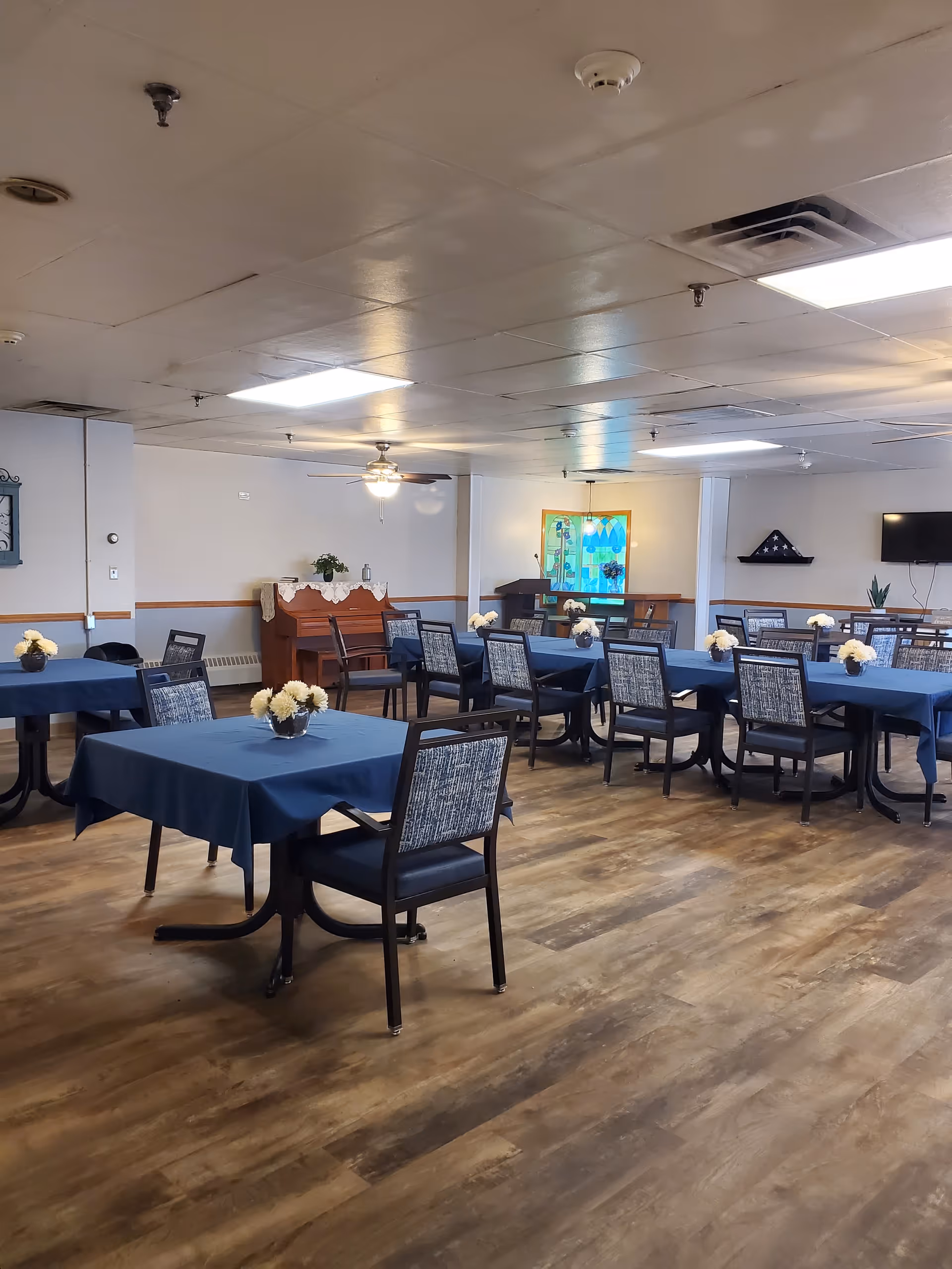 Senior living dining room with blue tablecloths and floral centerpieces