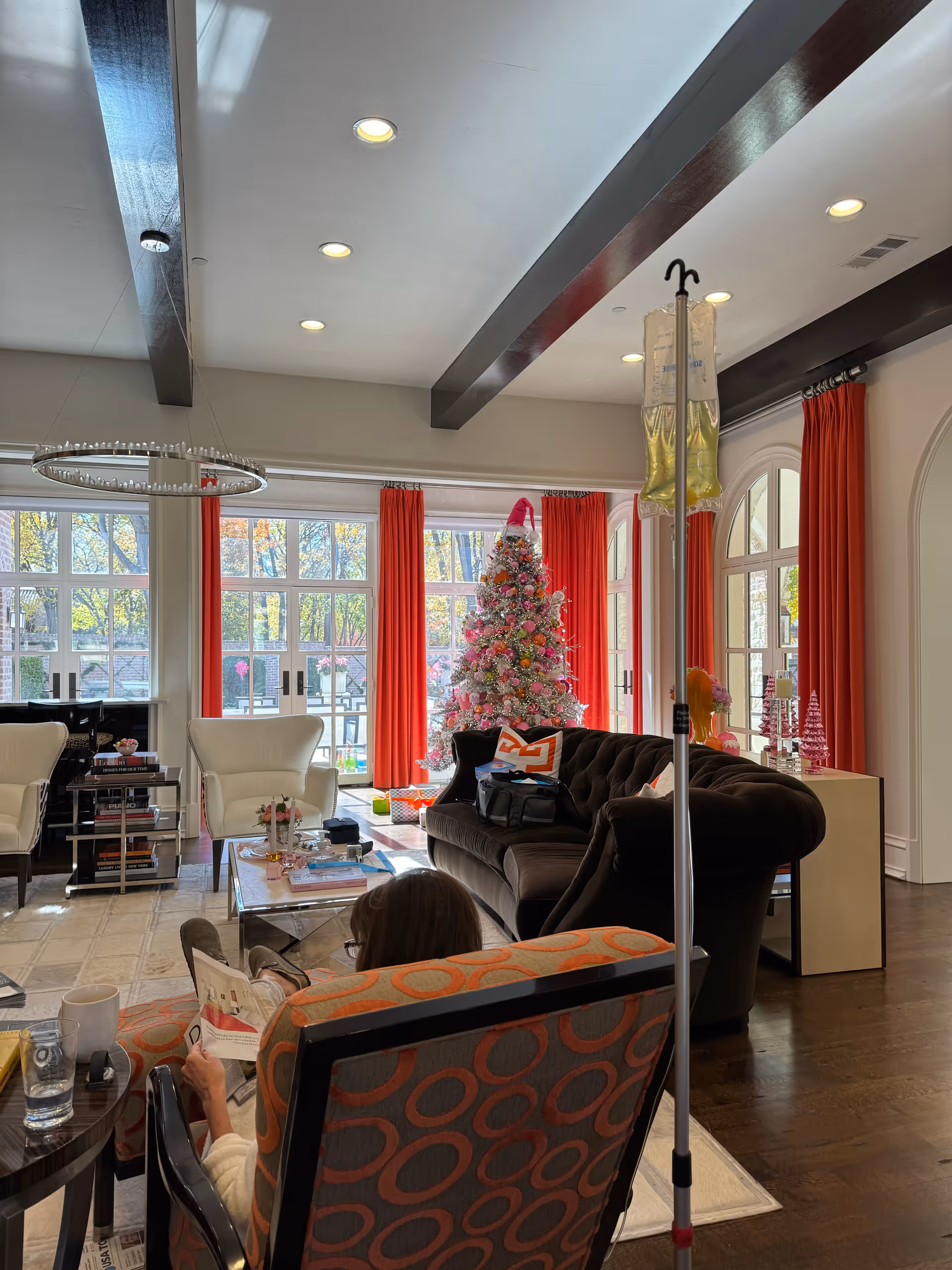 Cozy living room lounge with seating, a Christmas tree, red curtains, and a resident reading.
