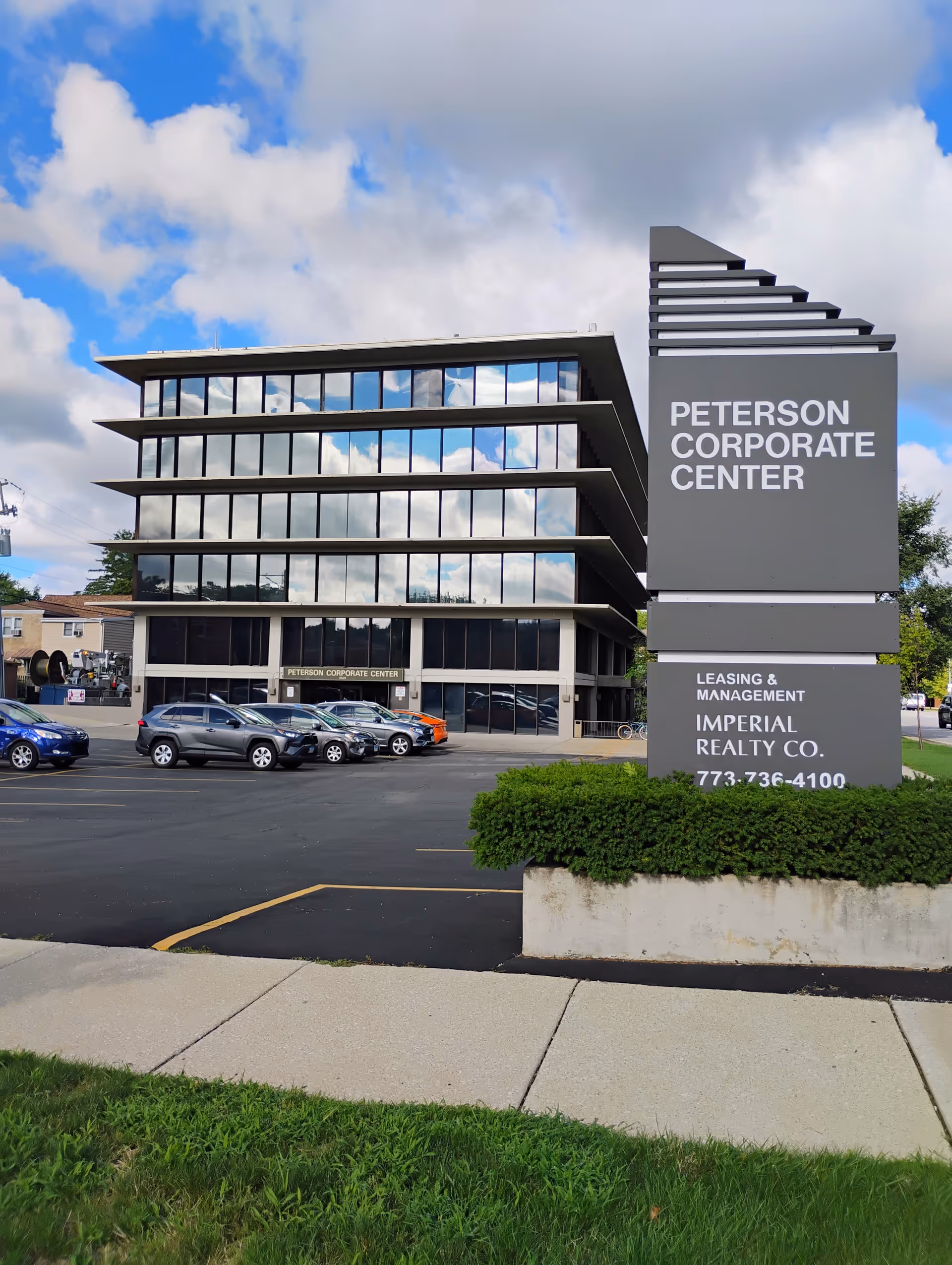 Modern glass-front corporate center with a tall sign advertising Peterson Corporate Center.