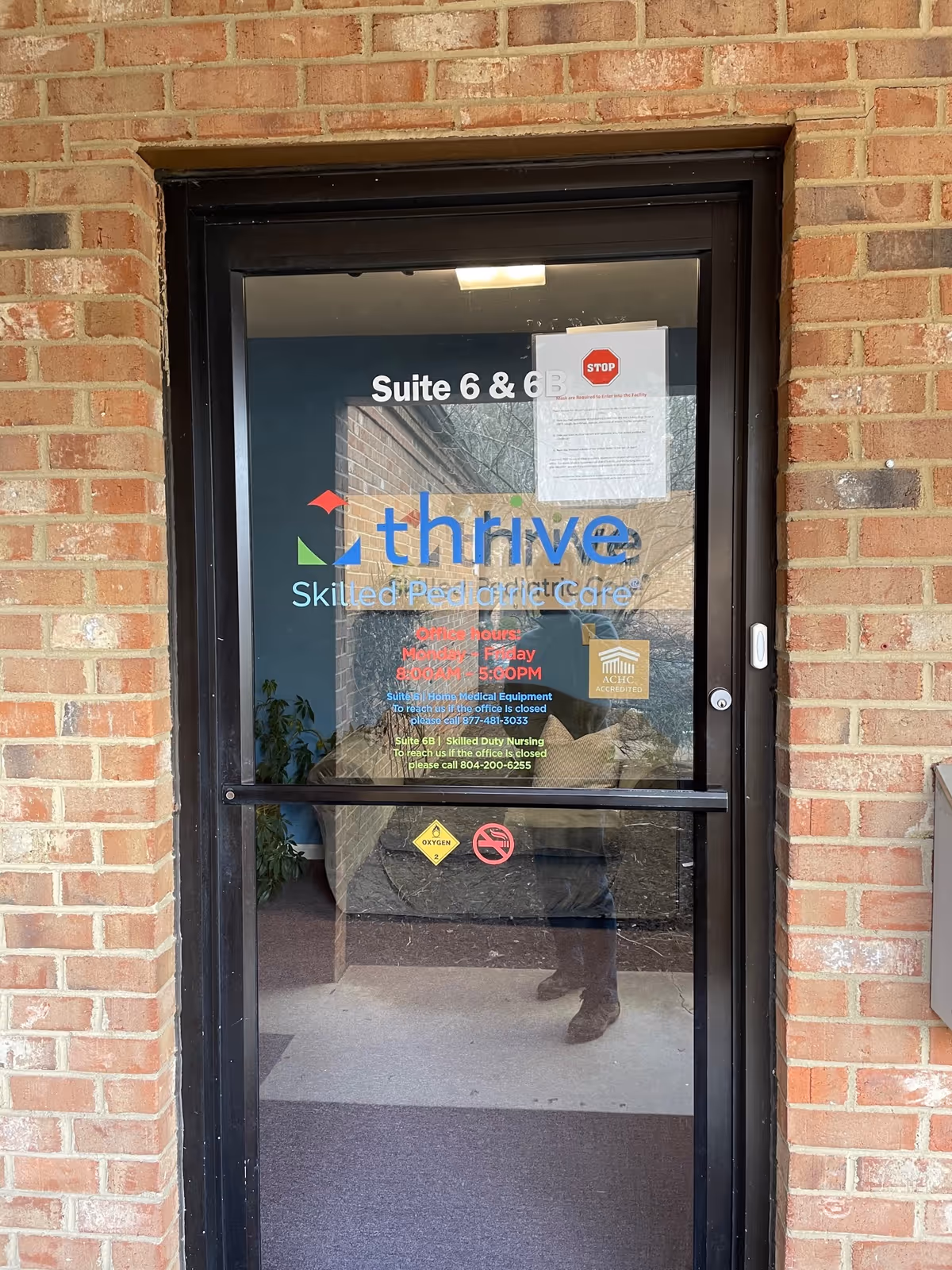 Brick exterior doorway with glass panel featuring Thrive logo and suite numbers.