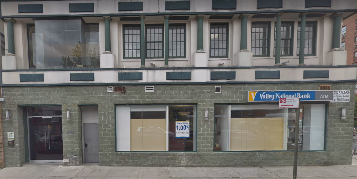 Street view of a green-brick building with a Valley National Bank storefront and ATM.