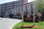 Exterior view of Bethany Health Care Center with sign and trees nearby