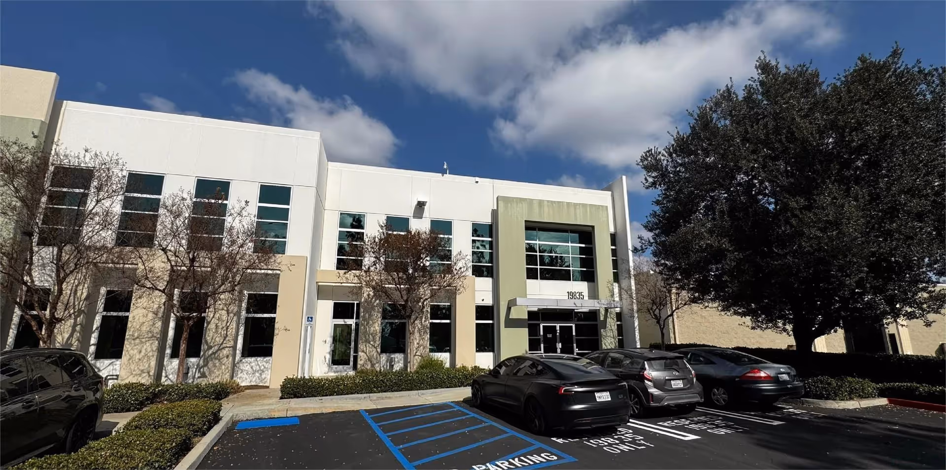 Front exterior of a modern medical building with glass windows and parked cars.