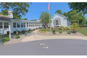 Wide view of Maple Farm Nursing Center front, with flagpole, walkway, and landscaping.