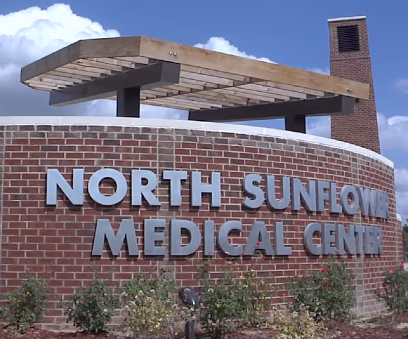 Exterior brick sign reading North Sunflower Medical Center with a wooden canopy.