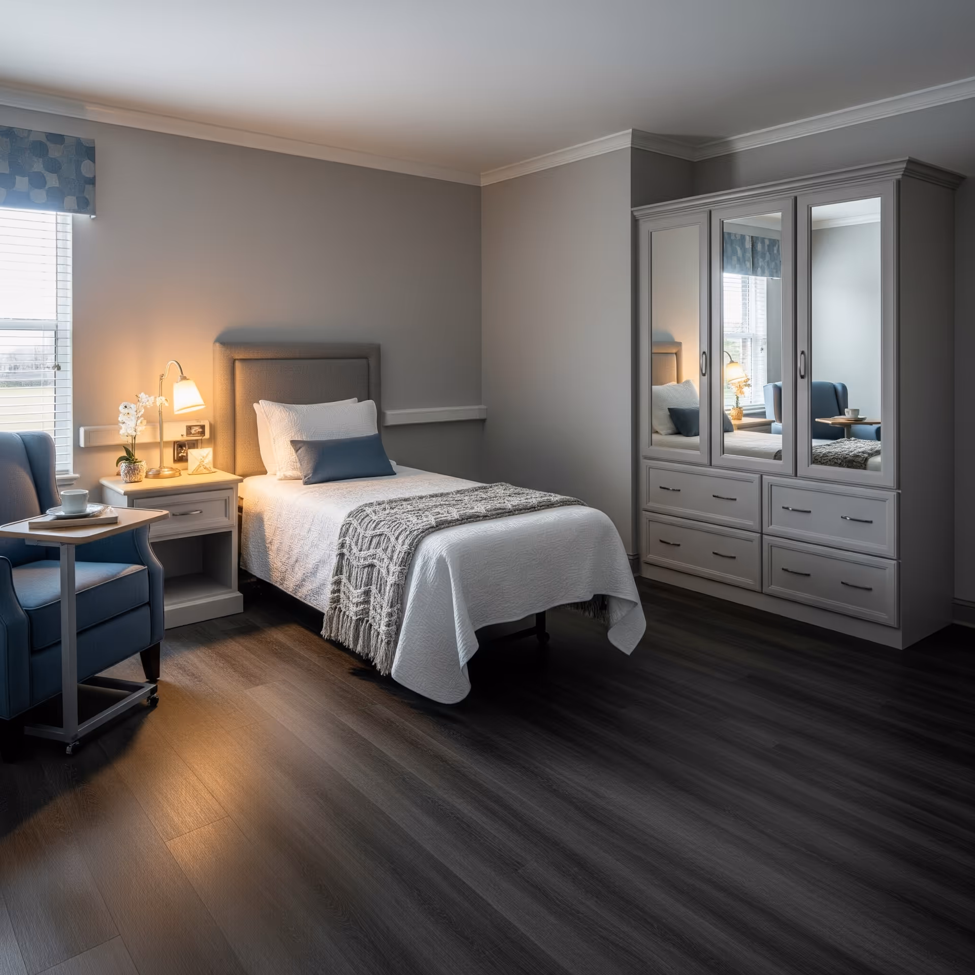 A neatly furnished senior living bedroom featuring a bed, dresser, and seating area.