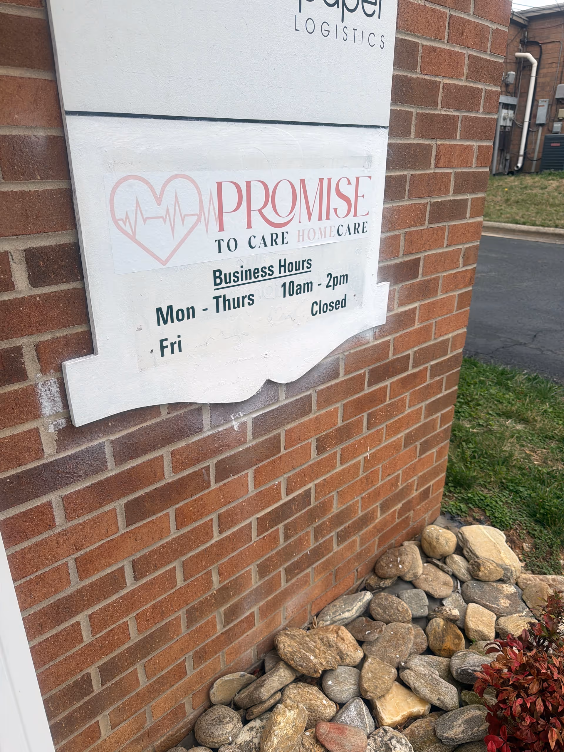 Brick building exterior with Promise To Care Home Care sign and rock landscaping.